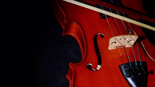 Violin, bow appearing and passing over the strings of a beautiful violin, 4k, selective focus.