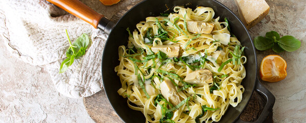 pan with pasta with spinach and artichokes on the table