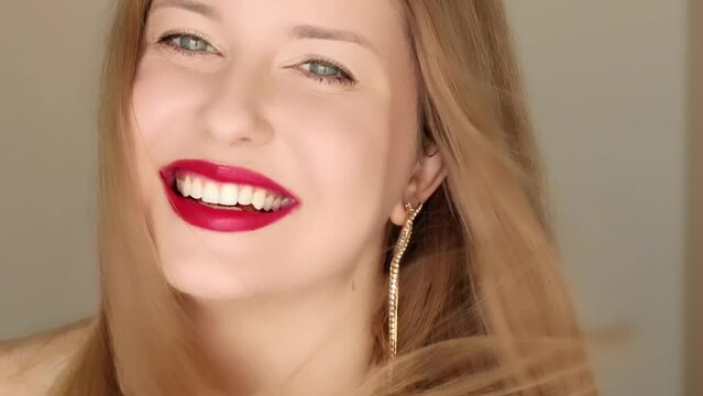 Happy woman smiling with perfect white teeth smile and posing in close-up portrait, female model with long hair wearing golden earrings and red lipstick make-up, jewellery fashion and beauty
