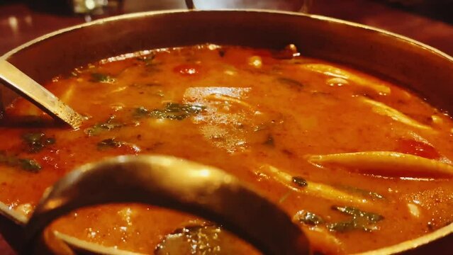 Steaming pot of spicy seafood soup, featuring a delightful mix of shrimp, calamari, and scallops, all infused with fragrant herbs and spices