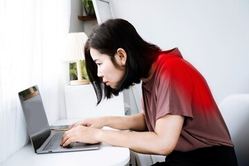 Asian woman's back and shoulder pain with incorrect posture while working on a computer and potential Kyphosis - obrazy, fototapety, plakaty