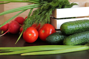Wooden white basket with fresh vegetables. A bunch of fresh vegetables in a basket on a wooden table