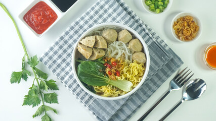 meatball, in Indonesia known as Bakso or Baso. Served with noodles vegetables chili sauce in a bowl on white background. Close up top view flat lay