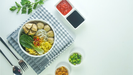 meatball, in Indonesia known as Bakso or Baso. Served with noodles vegetables chili sauce in a bowl on white background. Close up top view flat lay