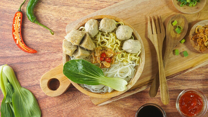 Meatball, in Indonesia known as Bakso or Baso. Served with noodles vegetables chili sauce in a bowl on wood background. Cclose up top view flat lay copy space