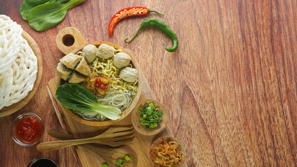 Meatball, in Indonesia known as Bakso or Baso. Served with noodles vegetables chili sauce in a bowl on wood background. Cclose up top view flat lay copy space