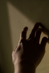View of a hand of a girl touches a wall in the light of morning sun
