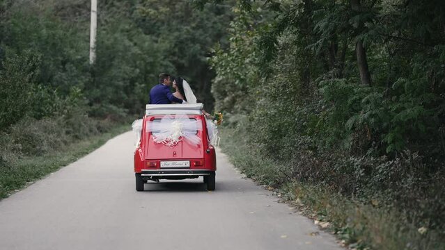 Dancing party just married couple having fun celebrate marriage driving in convertible vintage car, slow motion