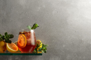 Iced tea with lemon and mint on the background of the grey concrete wall.