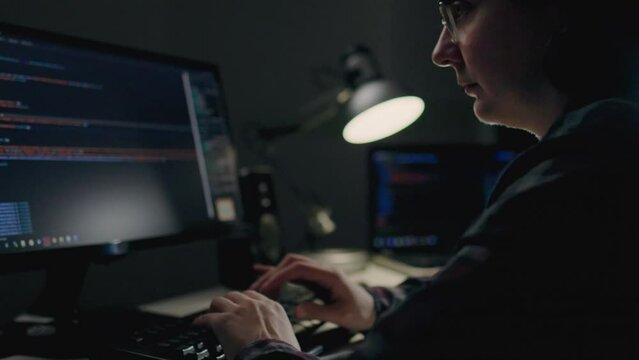 Home office, a programmer sits at a desk cluttered with computer equipment. Focused on the screen, they skillfully write lines of code, bringing software to life from the comfort of their own space
