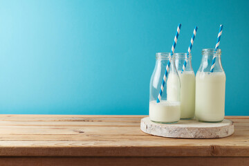 Milk bottles on wooden table over blue background