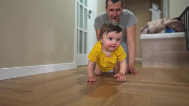 baby crawl first steps. dad play a baby toddler take crawl at home. happy family kid dream concept. baby daughter learning to take first steps indoors. dad teaches walk toddler lifestyle indoors