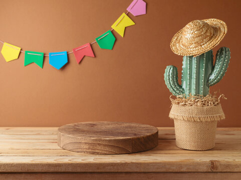 Festa Junina party background with empty podium, cactus and straw  hat decoration on wooden table. Brazilian summer harvest festival concept.