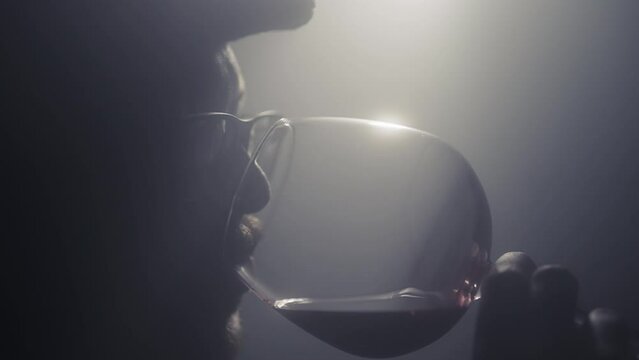Wine expert somellier smells and drinks wine alcoholic drink to give it rating, slow motion shot with cinematic atmosphere, light and fog