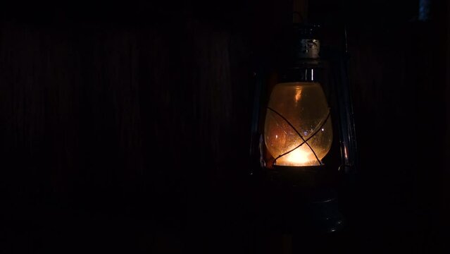 Lit hurricane warm reflected light lamp standing in a dark room. Kerosene lamp Close up views 4k video.