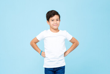 Cute mixed race boy smiling with arms akimbo in studio isolated light blue color background