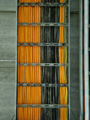 Selective focus of cable tray with electrical wiring arranged on ceiling . orange, and black cable