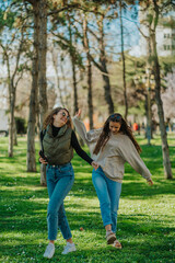 Naklejka na ściany i meble Beautiful girls having fun while walking on the grass in the park, on a beautiful sunny day
