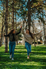 Two girls holding their hands, dancing and singing while walking in the park