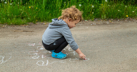 Children draw equations on the pavement with chalk. Selective focus.