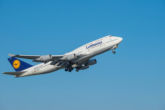 Close view of Lufthansa airlines Boeing 747-400 airplane with open chassis in blue sky after take off. Aircraft industry and air transport travel concept. 