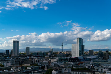 Fototapeta na wymiar Daytime of the urban Frankfurt skyline in autumn, featuring skyscrapers, cityscape, and partly cloudy blue sky, perfect for travel and business backgrounds.