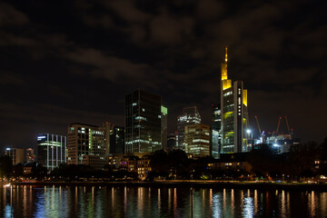 Fototapeta na wymiar Nighttime of Frankfurt cityscape highlighting the river, lit skyscrapers, and their reflection. Perfect for urban backgrounds and ads.