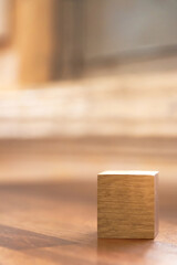 Blank wooden cube block on wooden table with shades of light through the window. Copy space for your text or number.