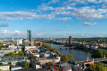 Daytime  of Frankfurt skyline featuring skyscrapers, bridge and river with partly cloudy skies during autumn season in Germany.