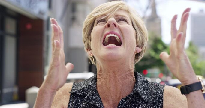 Face, stress and scream with a senior woman on a camcorder outdoor in the city for crazy expression. Portrait, mental health and shout with a mature female person on an urban street to show emotions