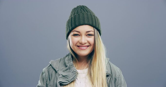 Portrait, happy and fashion with a woman in studio on a gray background to wear contemporary winter clothes. Smile, style and beanie with an attractive young female model in modern or trendy clothing