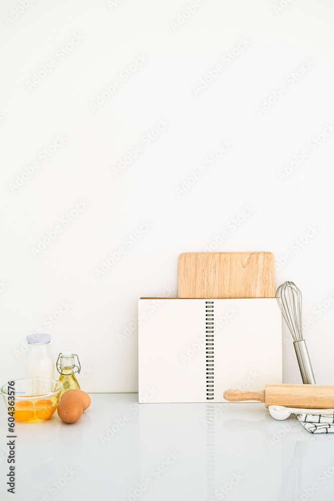 Wall mural blank page of book notepad paper opened and tablecloth on white table , recipes food for healthy habits shot note background concept. Front view with copy space.