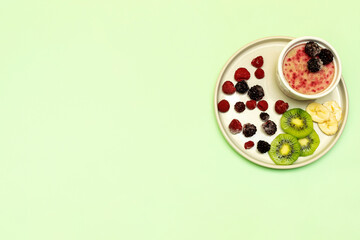 Sweet ice cream yogurt with frozen banana kiwi fruits, blackberry, raspberry berries. Cold fresh summer homemade dessert food on gray plate with copy space