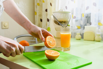 Woman is preparing fresh orange juice in the kitchen.