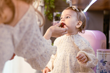 Mom feeding her baby girl with strawberries in the kitchen