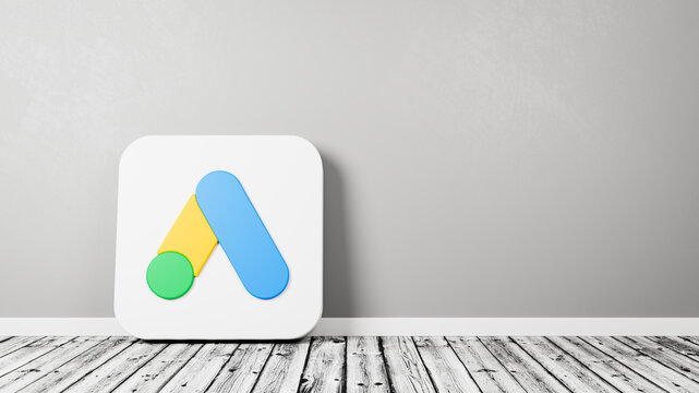 Google Ads App Icon on Wooden Floor Against Wall