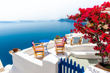 Santorini island, Greece. Beautiful terrace with red flowers and sea view.