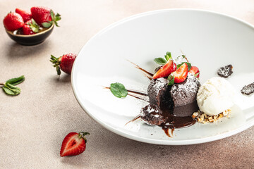 Chocolate fondant lava cake with strawberries, traditional french chocolate cake with liquid filling