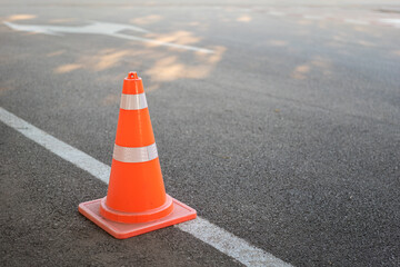 A safety traffic cone on the asphalt road. Transportation equipment object.