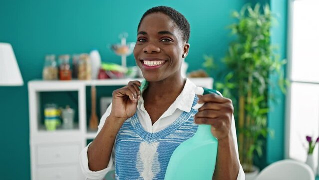 African american woman smiling confident holding clean products at dinning room