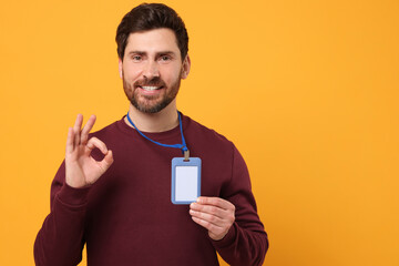 Smiling man with VIP pass badge showing OK gesture on orange background, space for text