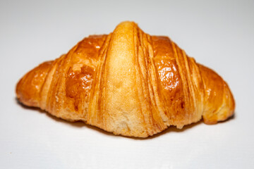 Golden brown butter croissant with shadow isolated on the plain background.