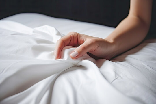 Female hand on soft bed pulling white sheets on bedroom hotel. Pleasure, erotic, ecstasy, orgasm, sex, intimacy and love and concept. Generative AI.
