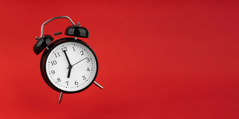 Black alarm clock on a red background.