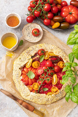 Cooking Homemade vegetable open pie galette with colorful tomatoes, ricotta cheese and fresh basil.	