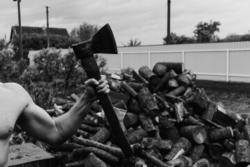 Woodcutter or lumberjack with the axe with wooden handle. The hatchet master. Harvesting firewood in the village. Jacked muscular man in the countryside. Eco farm lifestyle black and white.