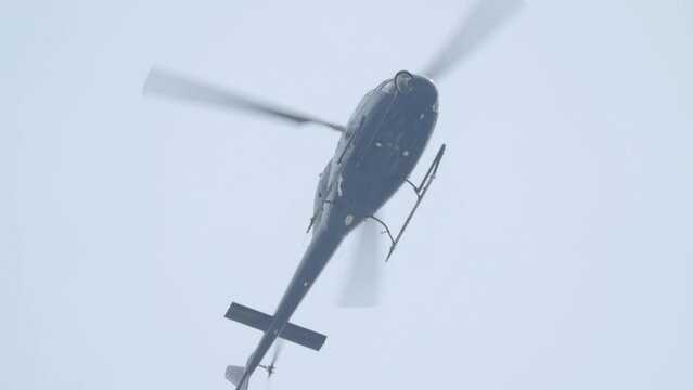 Helicopter flying in the sky low angle shot footage. Helicopter in flight. Capable of moving vertically and horizontally, the direction of motion being controlled by the pitch of the rotor blades.