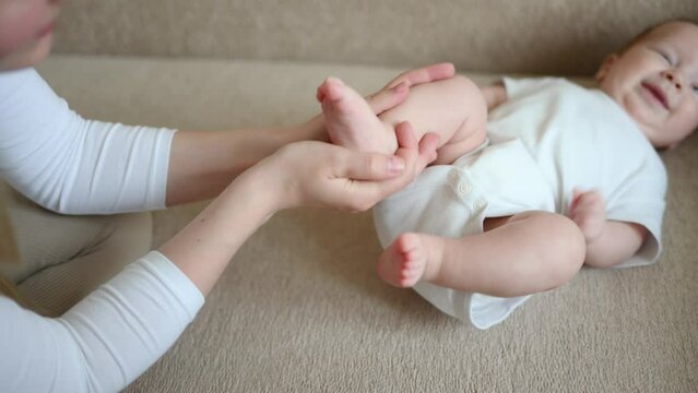 Mom massages the baby legs. Children massage.The concept of babysitting,maternity leave,masseur.Prevention of flat feet