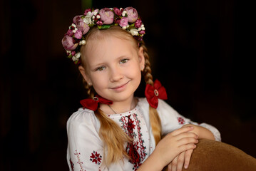 Portrait of a little Ukrainian girl with flowers in her hair. Ukrainian embroidered shirt.