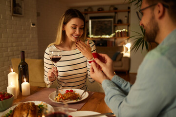 Surprised woman getting a marriage proposal over romantic dinner at home